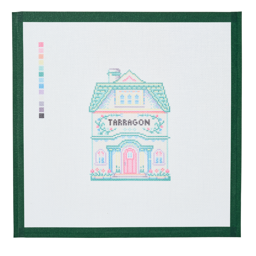 A needlepoint canvas of the Tarragon house, a small pastel building with its name on the front, on white mesh with a green taped edge.