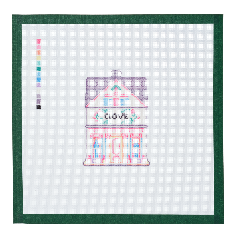 A needlepoint canvas of the Clove house, a small pastel building with its name on the front, on white mesh with a green taped edge.