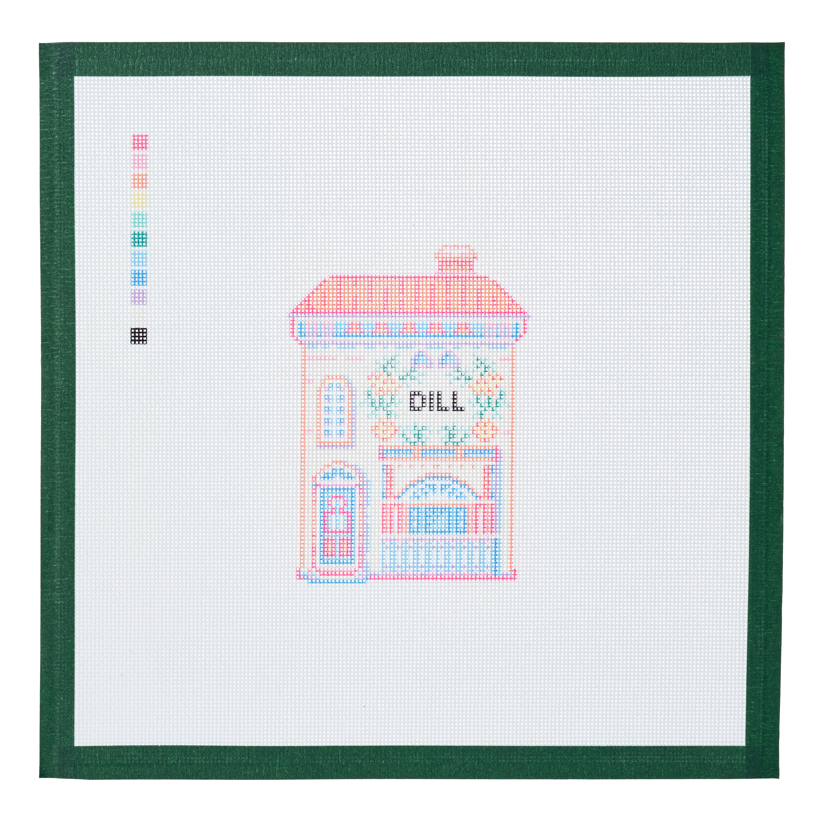 A needlepoint canvas of the Dill house, a small pastel building with its name on the front, on white mesh with a green taped edge.