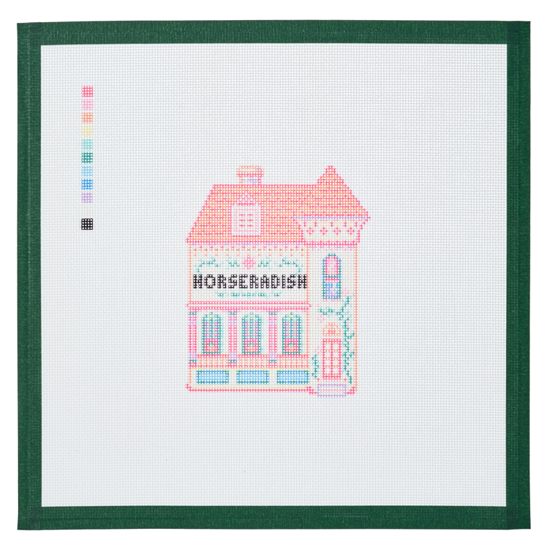 A needlepoint canvas of the Horseradish house, a pink and coral building with its name on the front, on white mesh with a green taped edge.