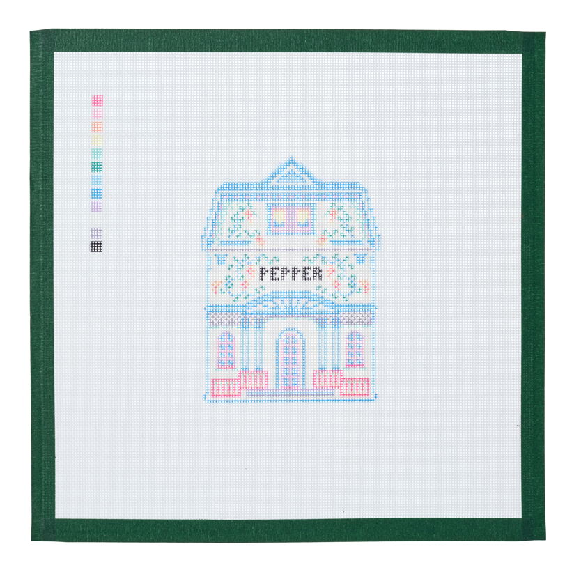 A needlepoint canvas of the Pepper house, a small pastel building with its name on the front, on white mesh with a green taped edge.