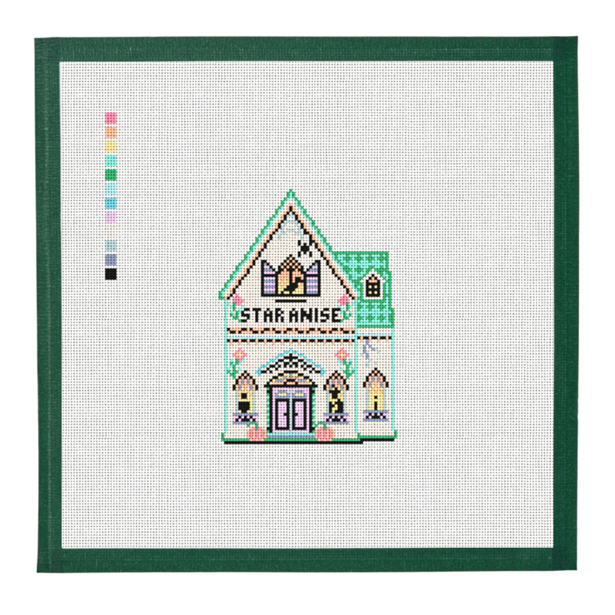 A needlepoint canvas of the Star Anise house from the Halloween Spice Village, on white mesh with a green taped edge.