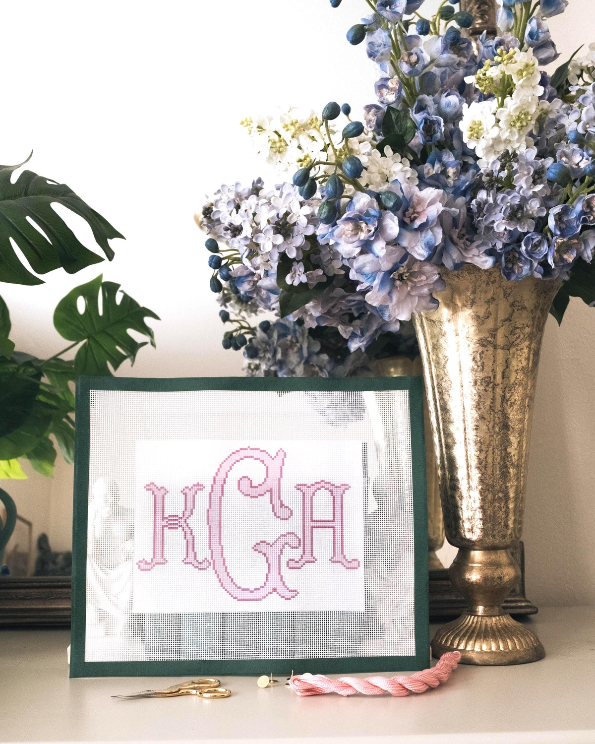 A custom monogram needlepoint canvas with printed initials on white mesh.